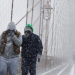 Peatones se protegen de la nieve y del viento mientras cruzan el puente de Brooklyn, en Nueva York